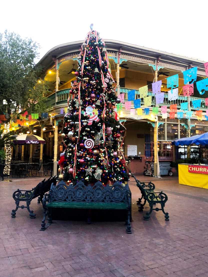 A Christmas tree with colorful flags in the background.