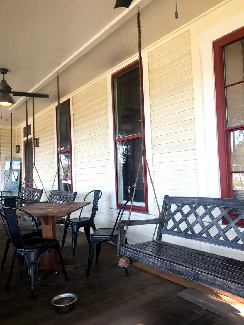 A porch a swinging bench next to a table and chairs A porch a swinging bench next to a table and chairs