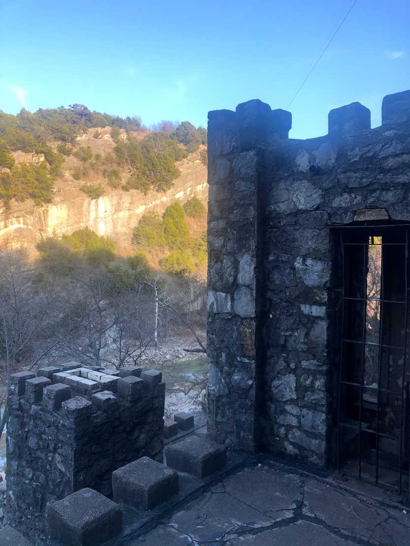 A castle structure with a rocky cliff view in the background.