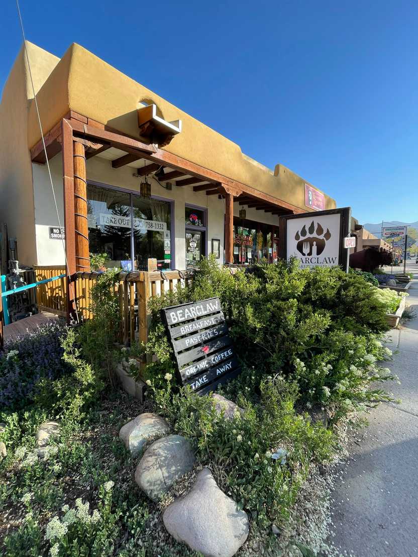 The exterior of Bearclaw Bakery. The building is a natural yellow color and there are several bushes in front of the storefront.