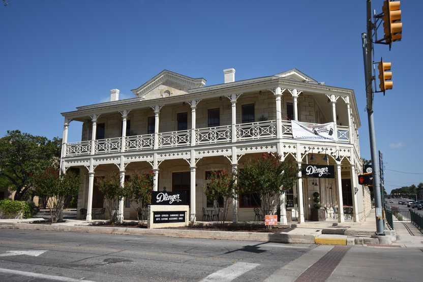 An elegant two story building with an intricate design on the railing of the second level.