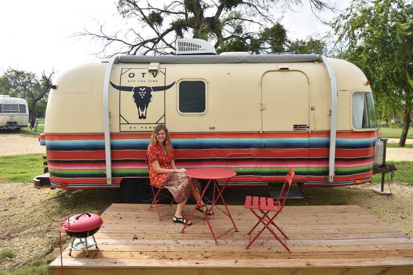 Lydia sitting outside of a colorful trailer at the Off the Vine RV resort in Hico, Texas.