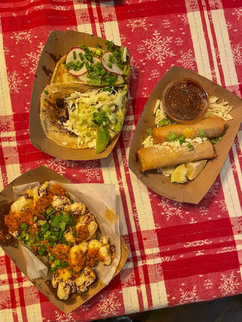 Three paper plates with cauliflower, egg rolls and tacos from Lloyd Taco Factory.