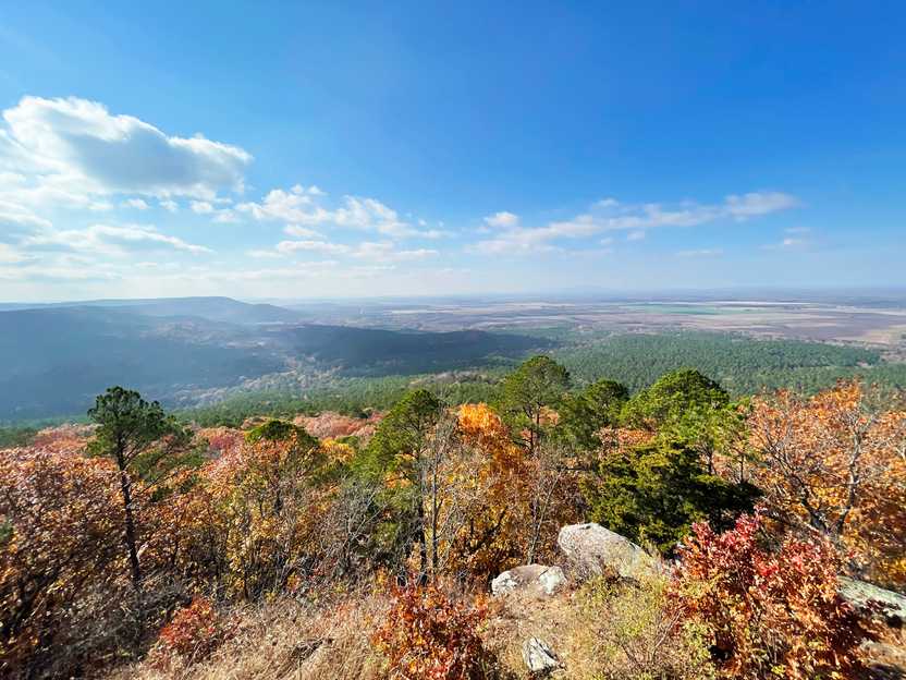 A viewpoint looking out into a valley. Many of the trees have yellow and orange leaves.