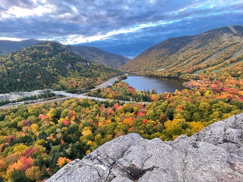 A small lake seen from above, surrounded by hills full of colorful foliage.