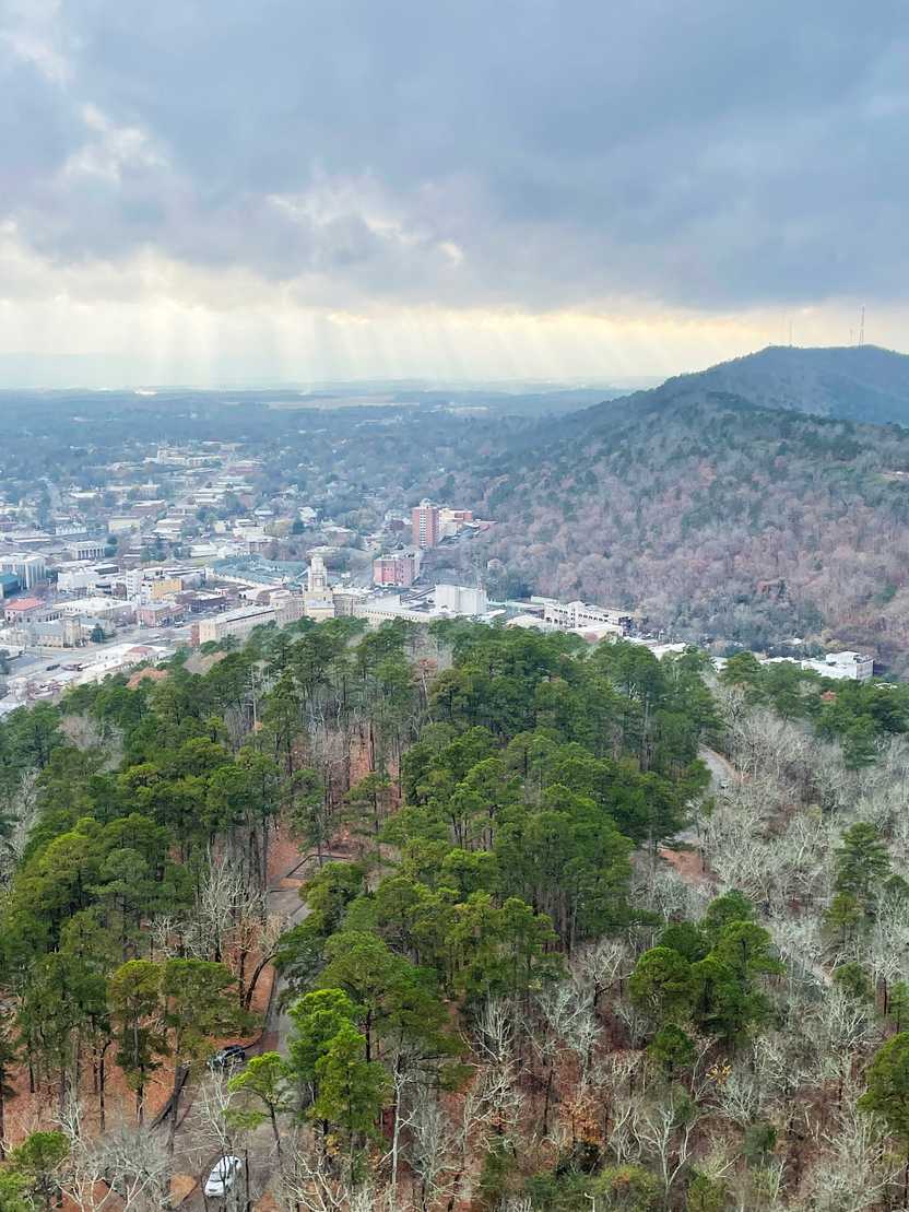 The view looking at downtown Hot Springs from the Hot Springs Mountain Tower. There is some red fall foliage on the hill behind the downtown area.
