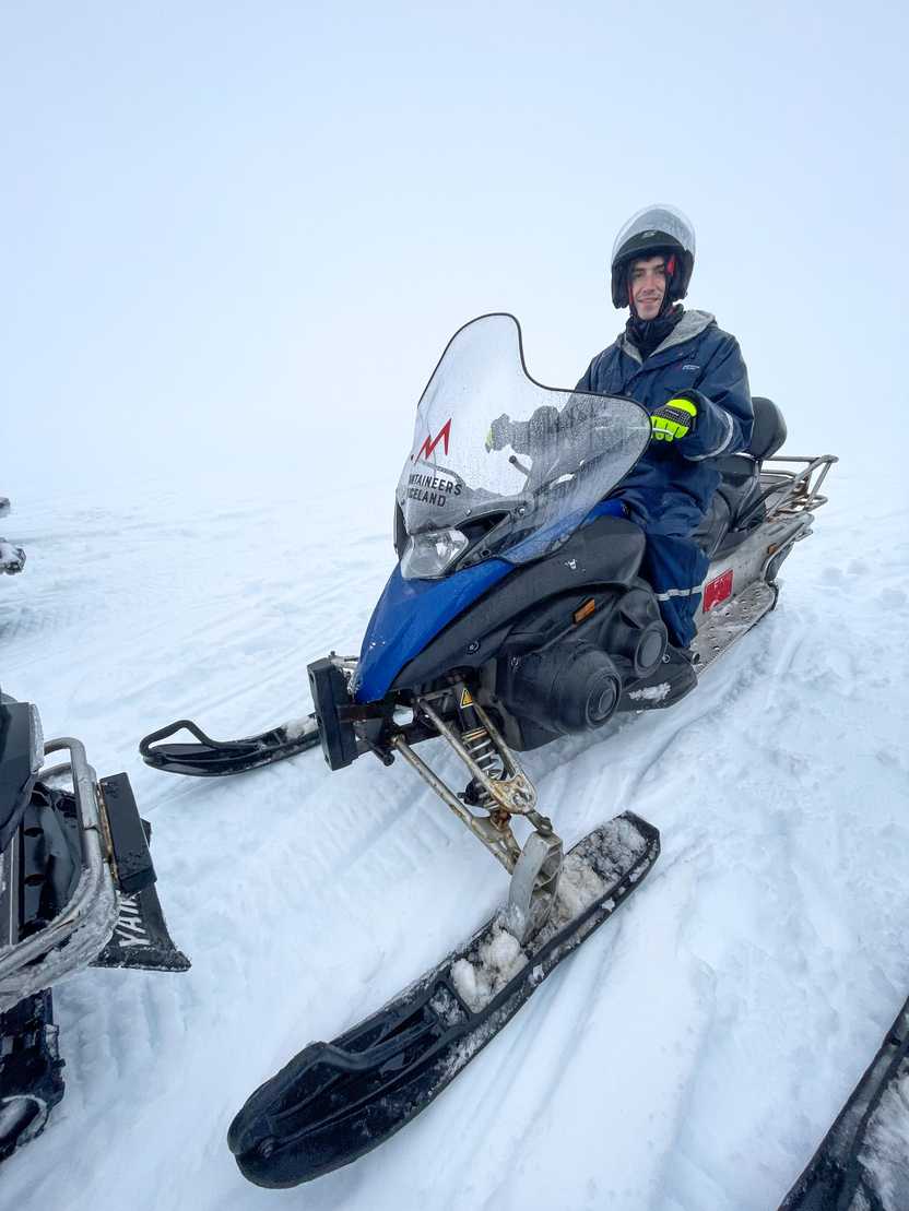 Joe sitting on a snowmobile wearing a snow suit.