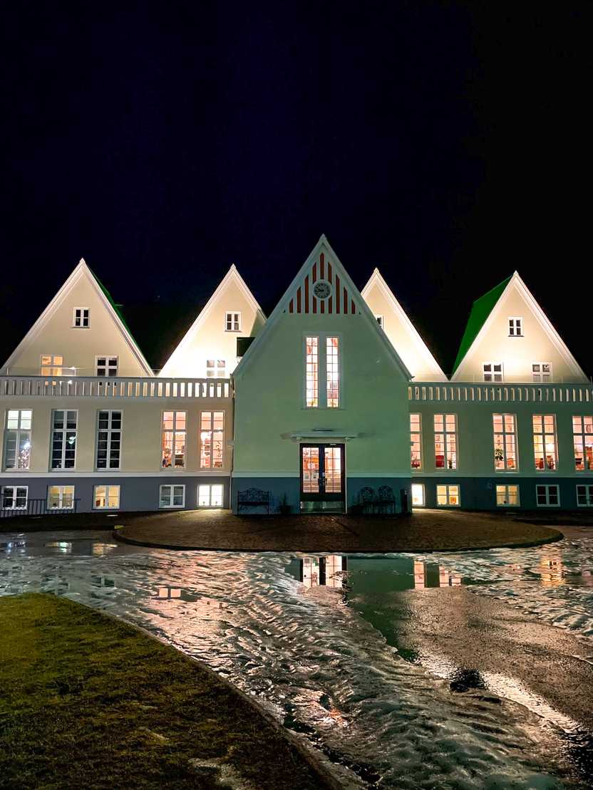 The exterior of Héraðsskólinn Historic Guesthouse, which resembled a guesthouse that is green and white.