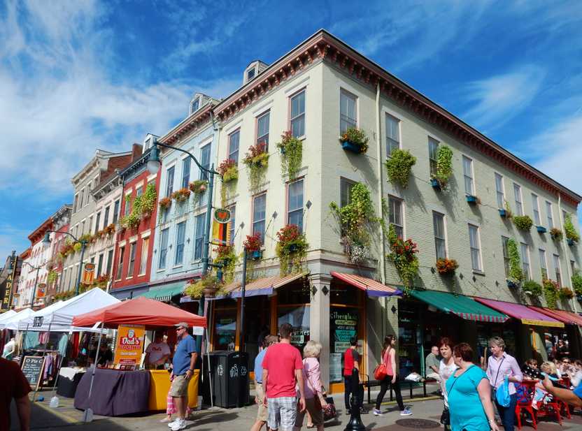 A corner of buildings located right next to Findlay Market. The window sills have plants and the home are various colors of blue, red and green.