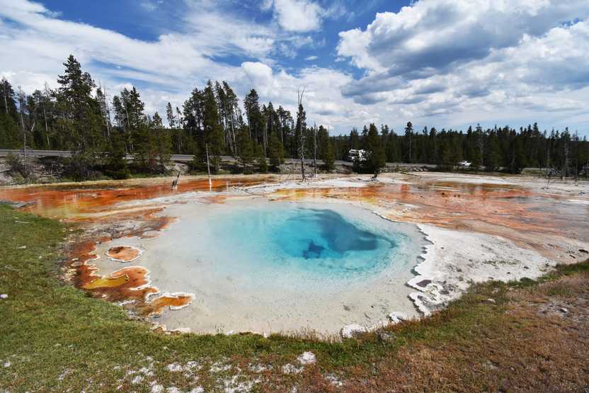 A bright blue spring surrounded by orange colors in the Fountain Paint Pots area of Yellowstone.