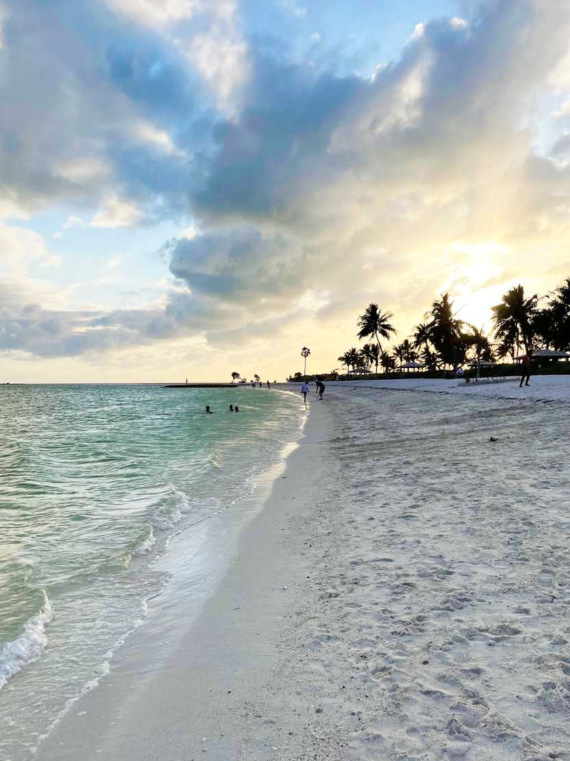 A sunset over Sombrero Beach. There is white sand, ocean and palm trees