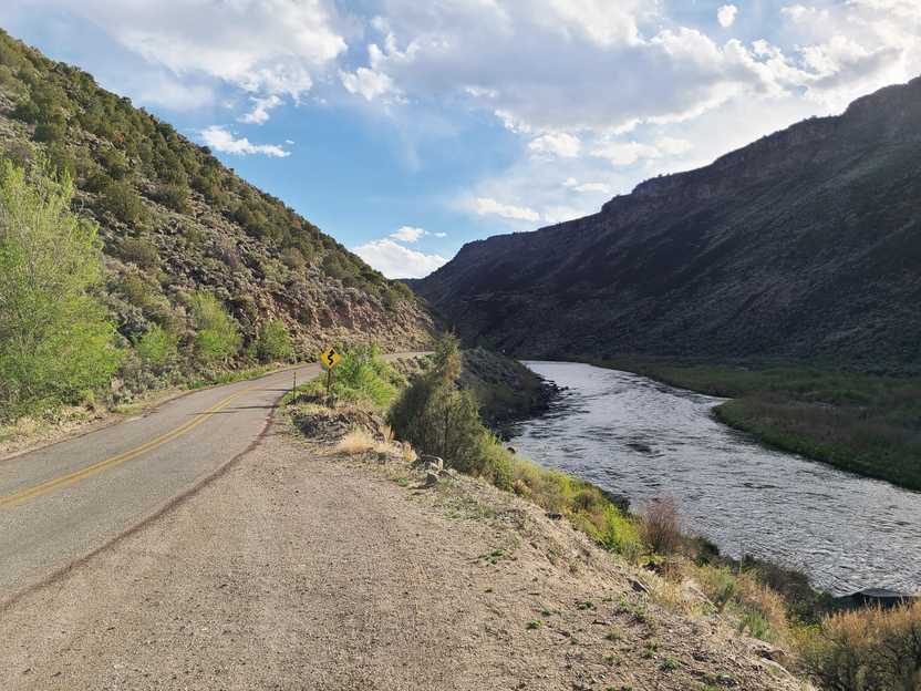 A road next to a river with a canyon walls on both sides.