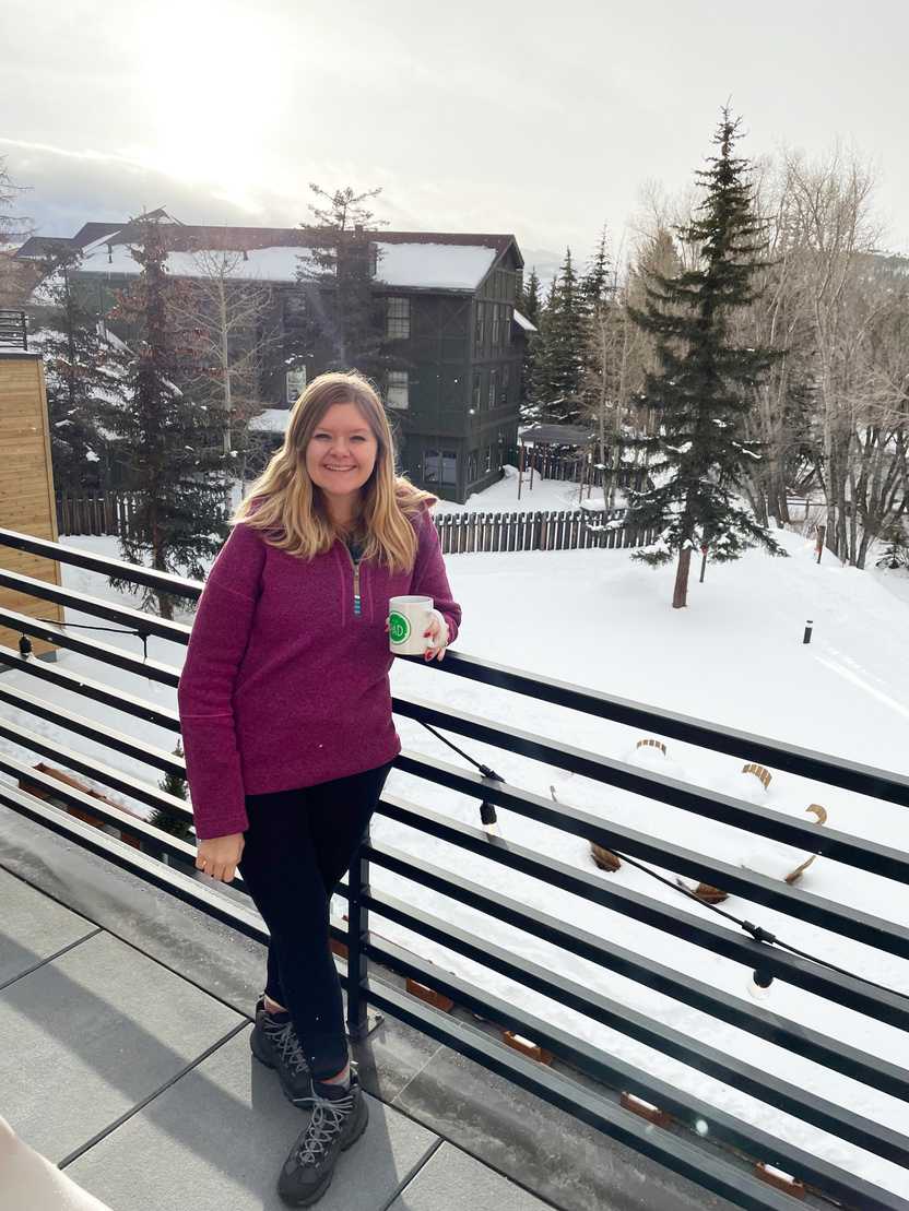 Lydia standing on the hot tub deck of The Pad holding a coffee mug, with snow on the ground in the background Lydia standing on the hot tub deck of The Pad holding a coffee mug, with snow on the ground in the background