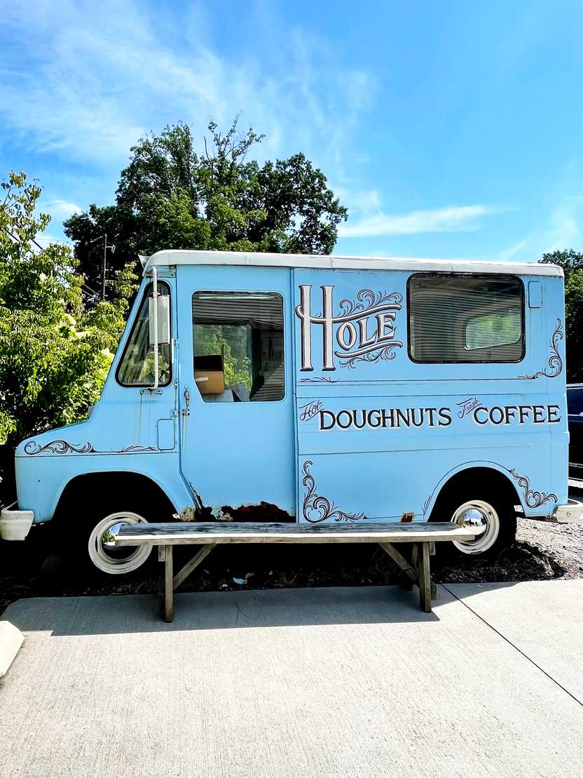 A small blue food truck that reads Hole: Doughnuts and Coffee