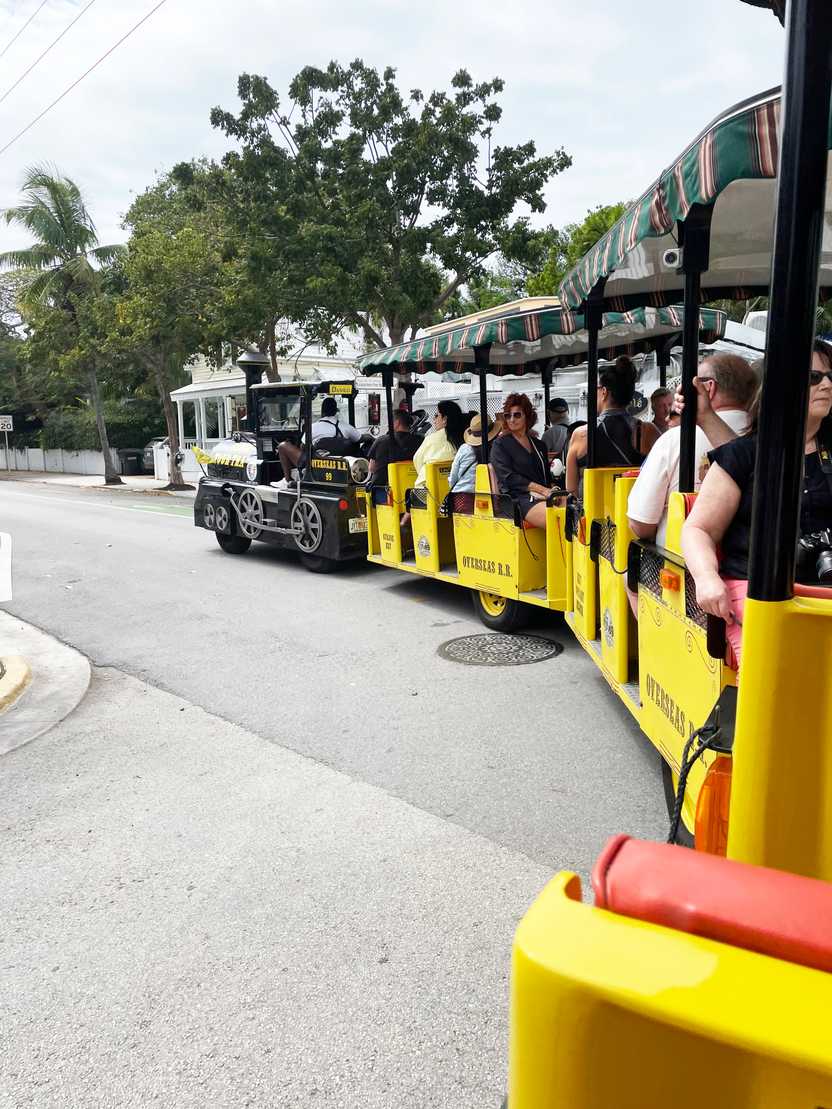 A side view of a yellow, open air train that is turning left