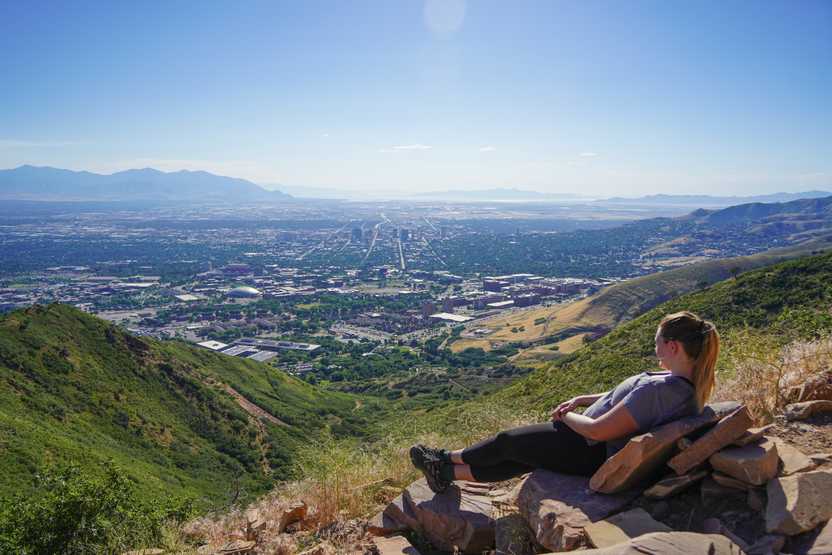 Lydia laying back on some rocks that resemble a couch with a view of the city below.