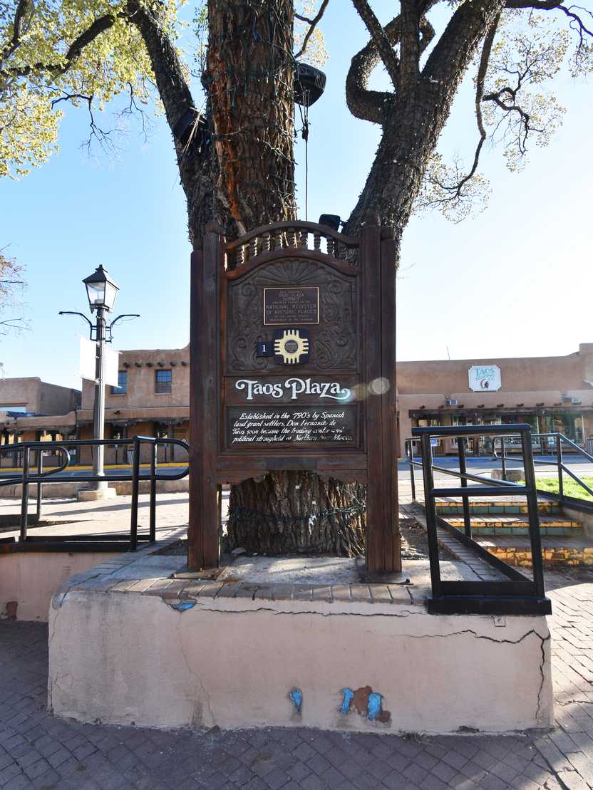 A large brown sign that says "Taos Plaza" with a brief history of the area.
