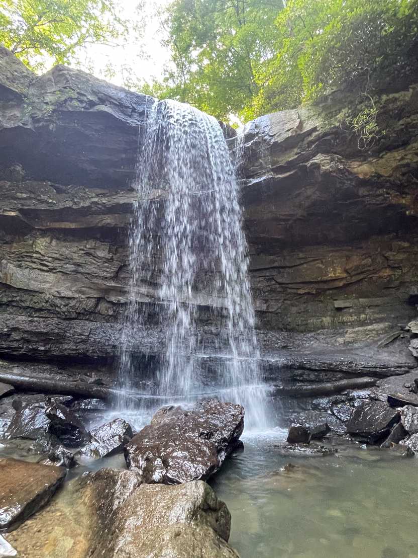 A close up view of a waterfall flowing over a rock overhang.