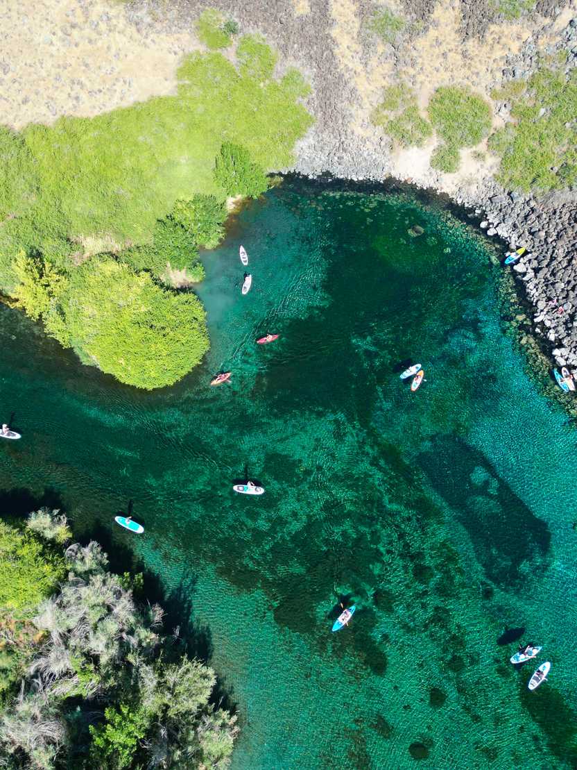 A drone shot of the heart-shaped Blue Heart Springs with several kayaks and paddle boards in the water. A drone shot of the heart-shaped Blue Heart Springs with several kayaks and paddle boards in the water.