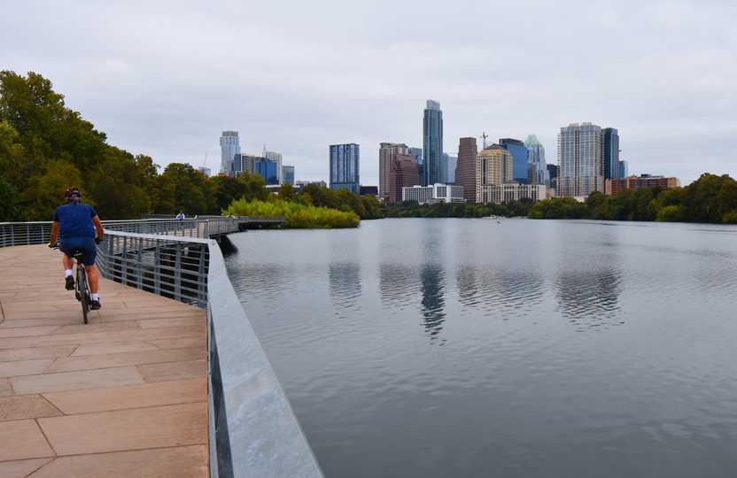 A biker along a boardwalk trail that borders Lady Bird Lake.