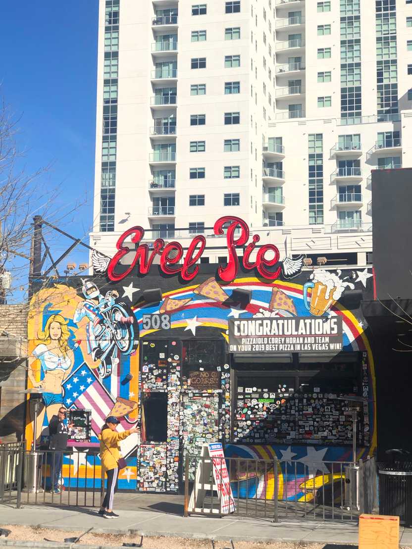 The exterior of Evel Pie Pizza. The building is very colorful with artwork that includes a rainbow, a motorcyle, pizza, beer and an American flag