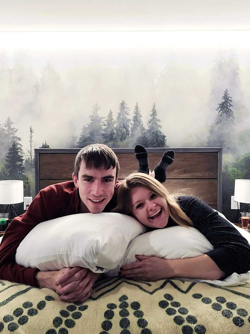 Lydia and Joe laying on their stomach on the bed in their room in The Pad. There is a beautiful scene of snowy trees in the background Lydia and Joe laying on their stomach on the bed in their room in The Pad. There is a beautiful scene of snowy trees in the background