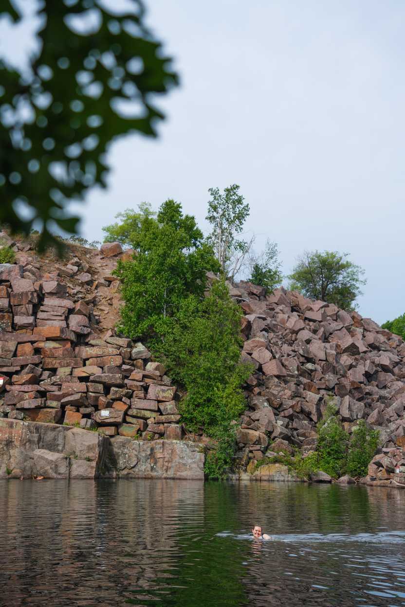 A large piles of quarry rocks next to a pool of water. A large piles of quarry rocks next to a pool of water.