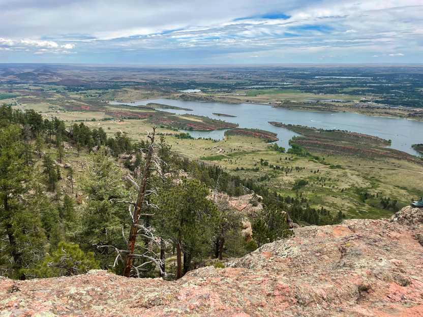 A view looking down at a valley with a large reservoir full of blue water. There are many green trees in the distance.