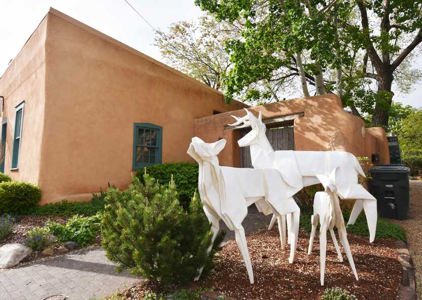 A Pueblo style building with two sculptures of white deer in front of it. This is an example of the outdoor sculptures on Canyon Road.