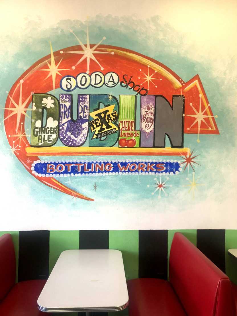 A red booth in the Old Doc's Soda Shop. On the wall, there is a mural for the Dublin soda shop