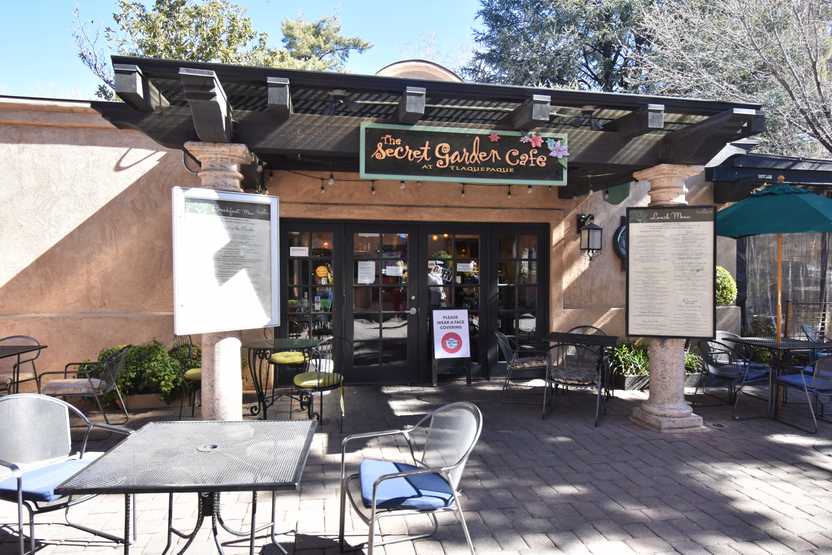 The exterior of The Secret Garden Cafe. There are menus and a table in front of the building.