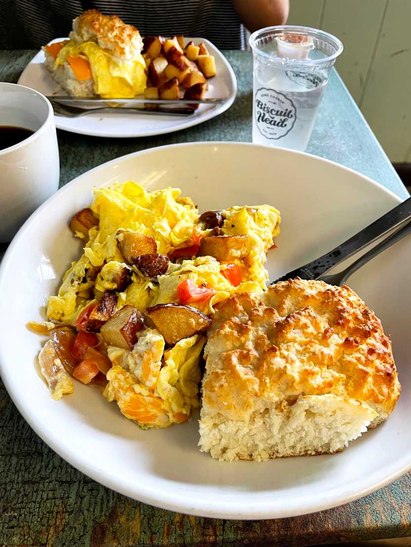 A plate with a large biscuit and a side of eggs and potatoes from Biscuit Head.
