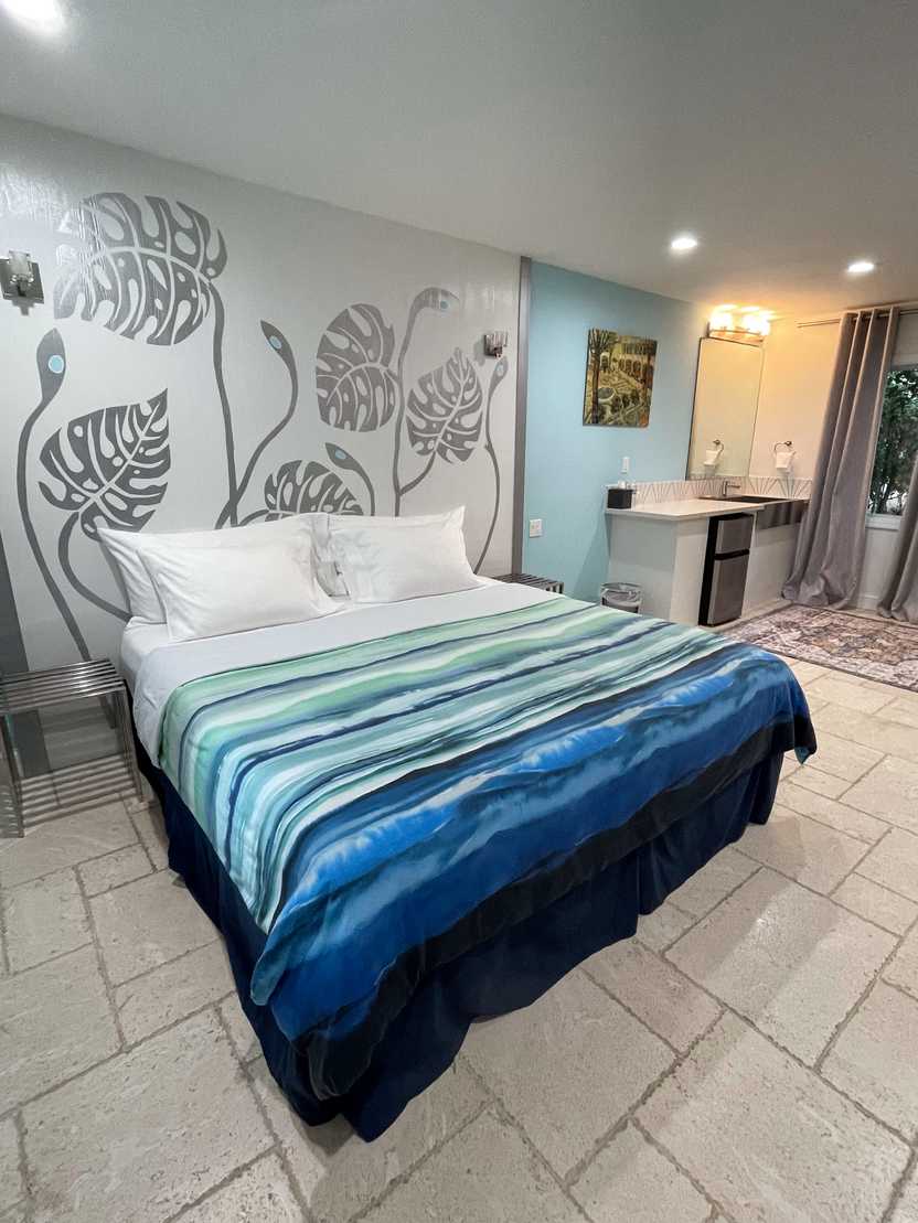 A bed with blue and green strips inside the Retreat at Crystal Manatee Hotel.