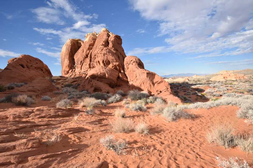 An orange rock formation surrounded by orange sand in Valley of Fire.