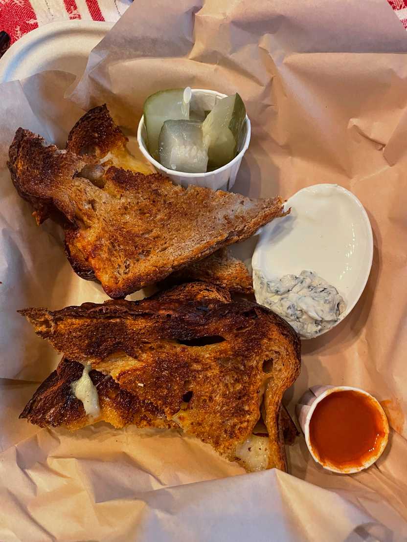 Four slices of bread that have cheese baked into them, served with hot sauce, pickles and a white sauce.