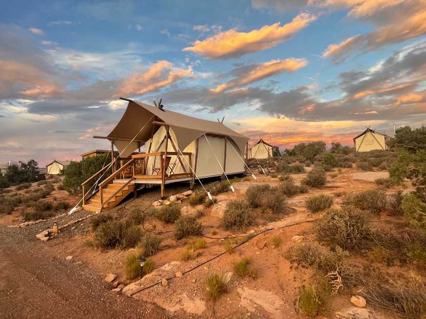 A few of the glamping canvas tents at Under Canvas in Moab. The sky is lit up at sunset.