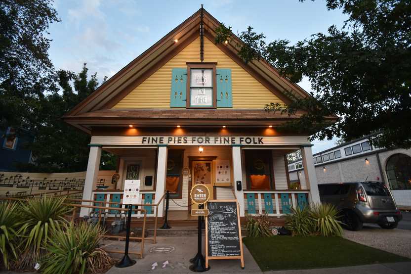 The exterior of Emporium Pies in Bishop Arts. The pie shop looks like a house painted white, yellow and blue.