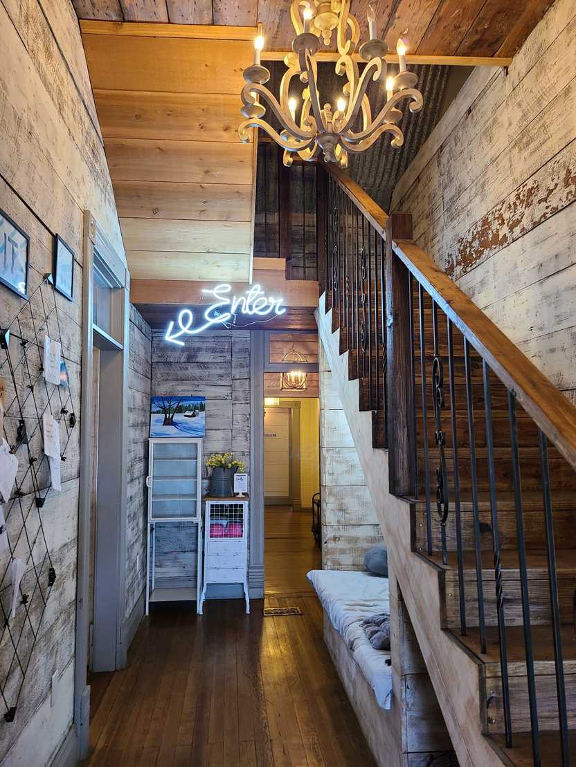 The interior of 2nd Street Bakeshop. There is a staircase, a chandelier and distressed wood on the walls. In the back of the hallway, a neon sign reads Enter with an arrow pointing left. The interior of 2nd Street Bakeshop. There is a staircase, a chandelier and distressed wood on the walls. In the back of the hallway, a neon sign reads Enter with an arrow pointing left.