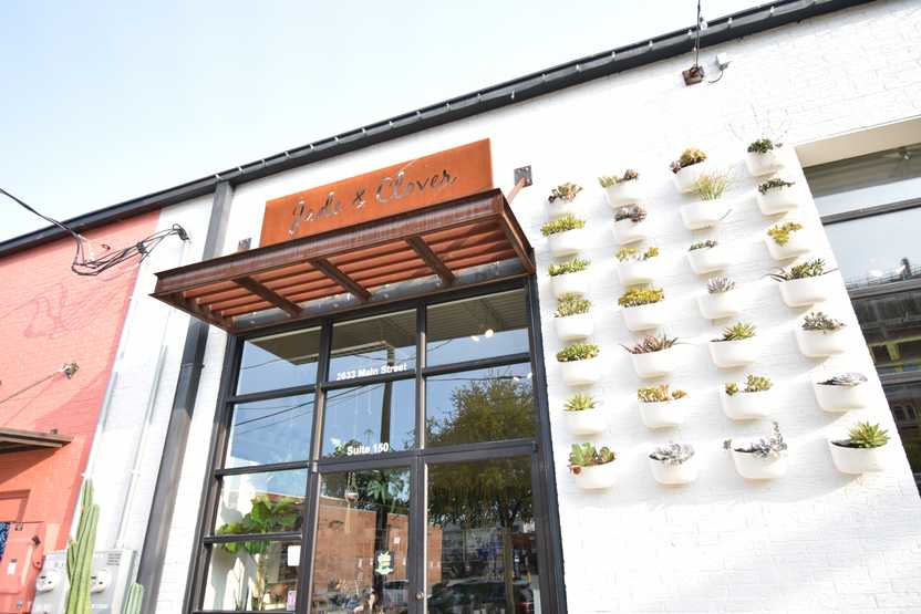 The exterior of Jade & Clover. There are several rows of white planters full of succulents.